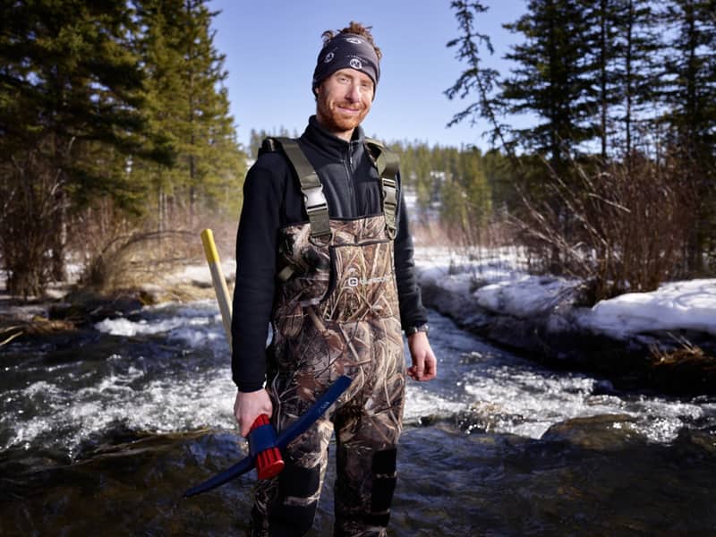 Benoit Turcotte wearing a toque and waders and carrying an axe