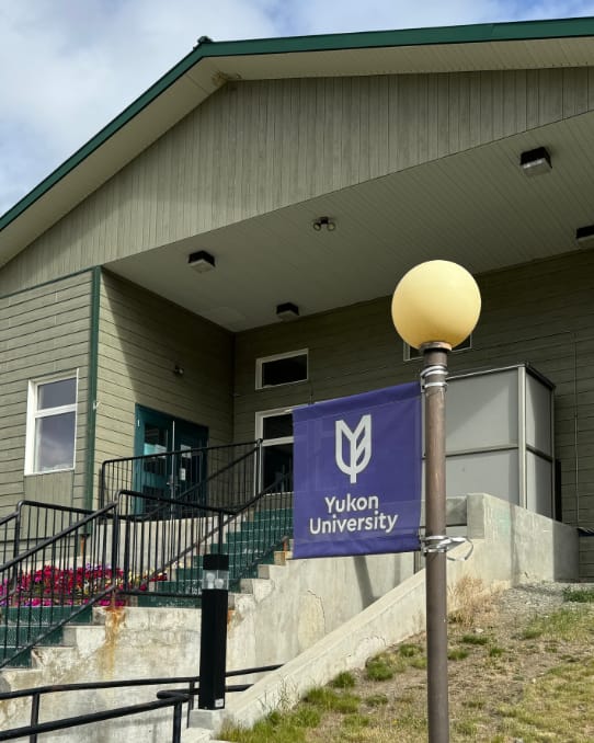 Front entrance of the Haines Junction campus with a purple Yukon University banner in the foreground