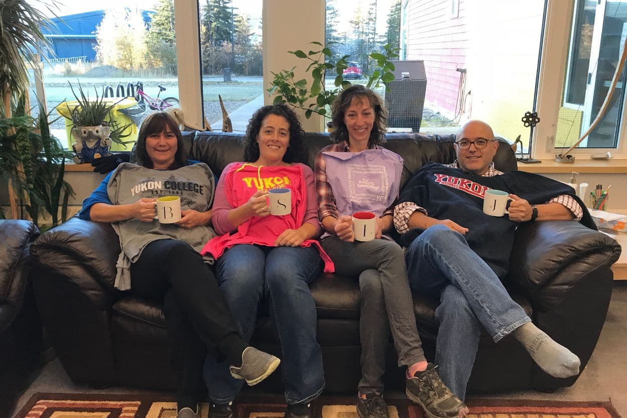 Staff of the Mayo campus seated on a couch with Yukon College shirts, each of them holding a coffee mug