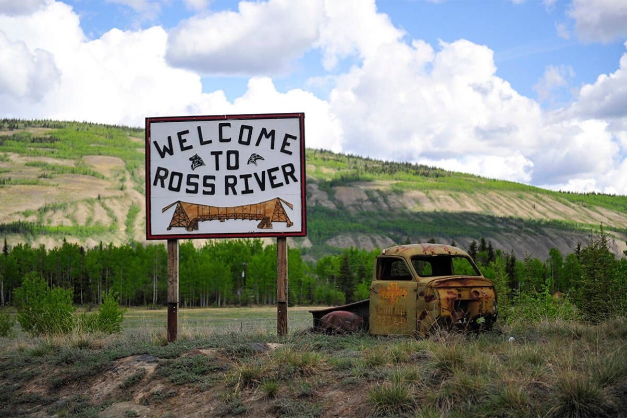 A "Welcome to Ross River" sign next to an "antique" truck