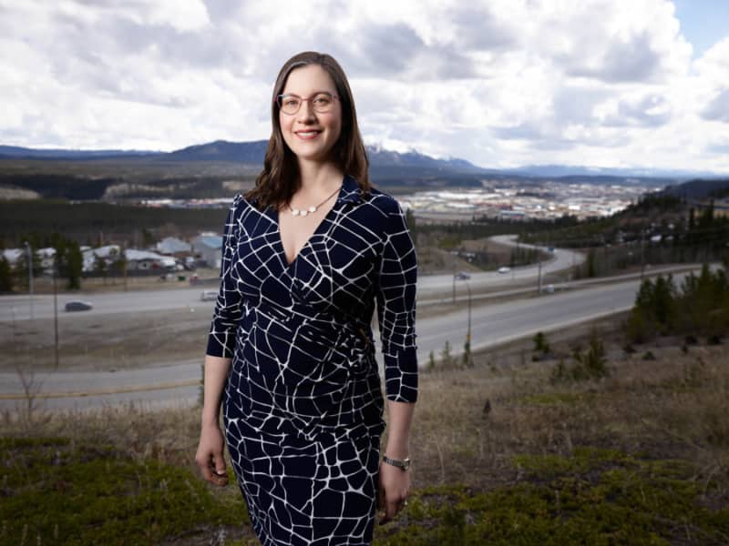 Sara McPhee-Knowles poses outdoors with downtown Whitehorse in the background