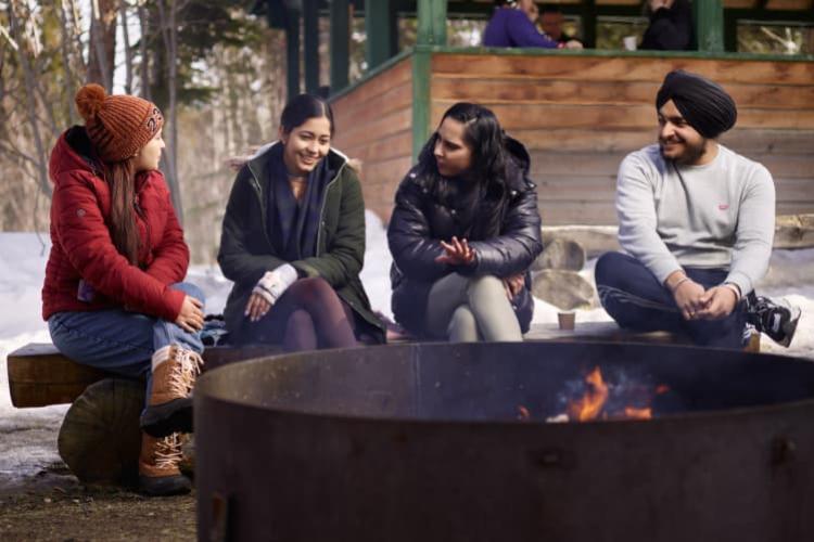 Four students sitting next to a fire pit and having a conversation