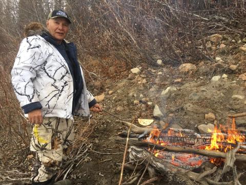 Stanley Njootli outdoors tending to a fire