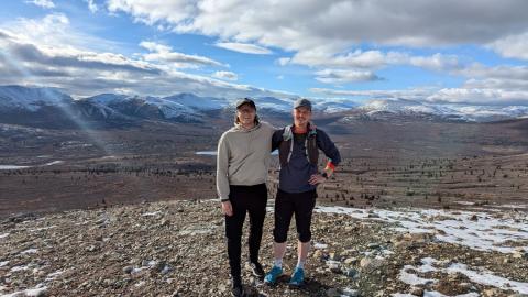 two men standing on top of a mountain