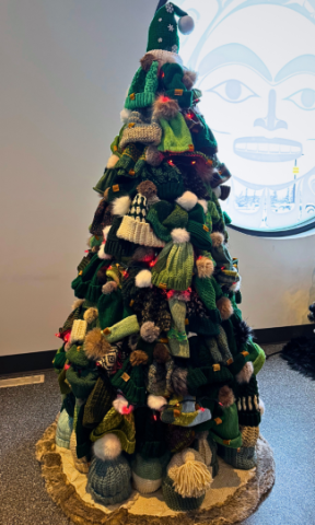 A tree full of green toques stands in a room