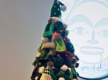 A tree full of green toques stands in a room