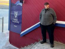 man standing in front of YukonU Faro campus sign