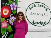 Woman stands in front of building with flowers and logo