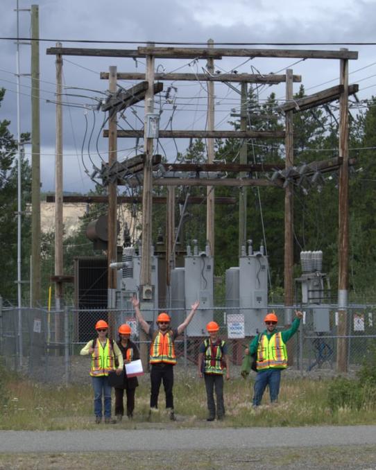 YukonU Northern Energy Innovation students and staff stand in front of a electrical sub-station