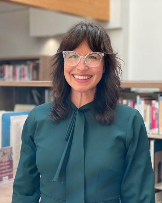 Portrait of Wendy Sokolon posing in front of shelves of library books