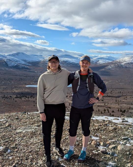 two men standing on top of a mountain