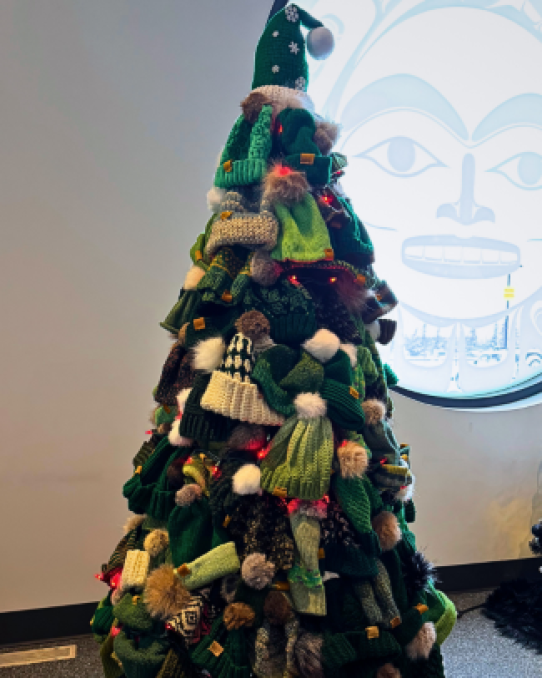 A tree full of green toques stands in a room